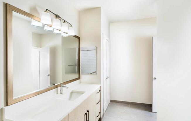 Primary bathroom with a long quartz vanity, integrated lighting, and clean-lined cabinetry arranged for an organized, comfortable daily routine.