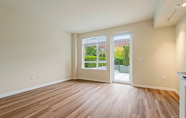 A room with wooden flooring and a view of a garden through the window.