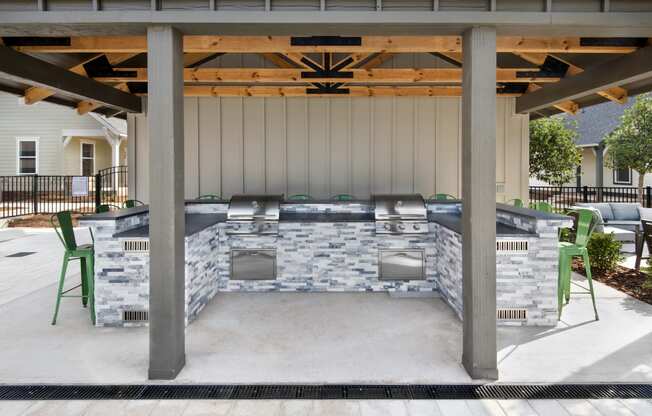 a covered patio with a barbecue grill and chairs