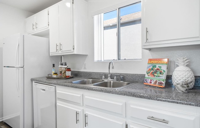 a kitchen with white cabinets and granite counter top and a sink