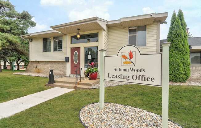 A sign for Autumn Woods Leasing Office in front of a building.