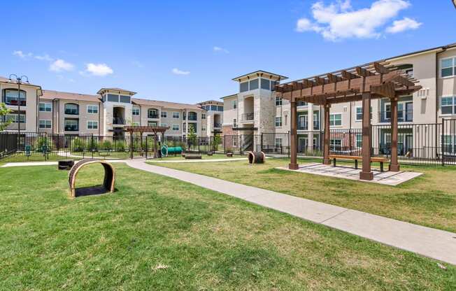 San Marcos Apartments for Rent-Sadler House-Dog Park-Grass, Wood Bench, Dog Tunnels, Paved Pathway, and Canopy