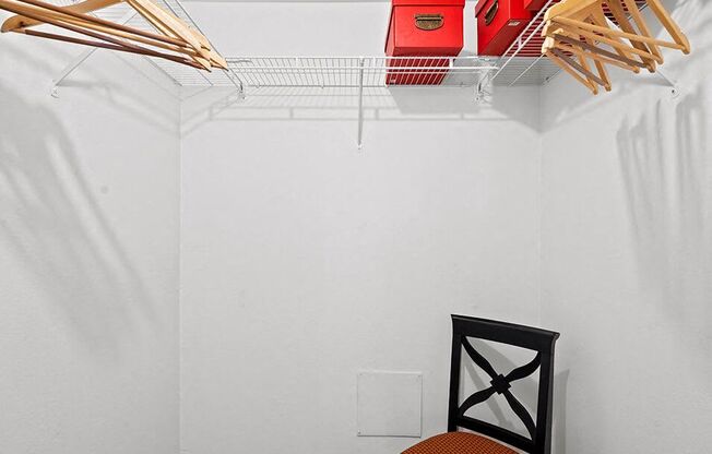 a white closet with a chair and a rack on the wall