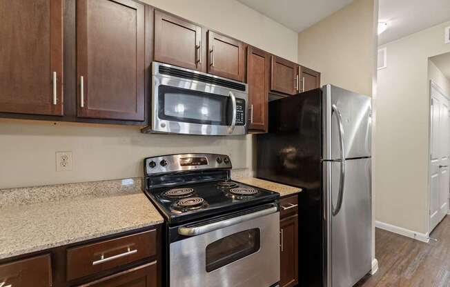 A kitchen with a stove, microwave, and refrigerator.