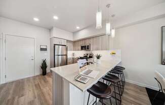 A kitchen with a bar area and a laptop on the counter.