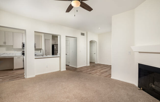 an empty living room with a fireplace and a ceiling fan