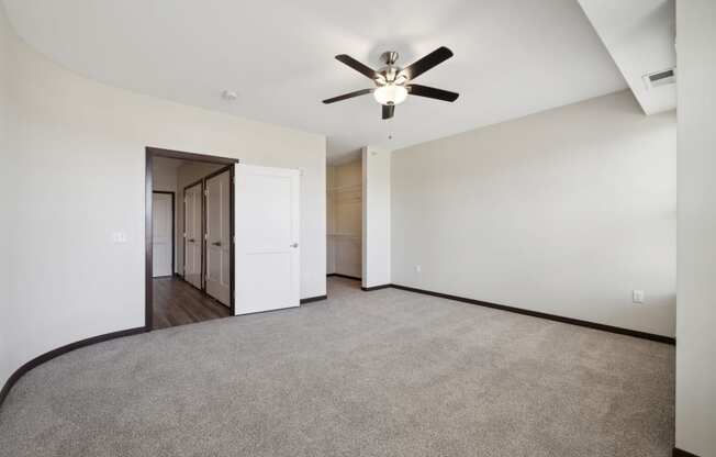 an empty living room with a ceiling fan and white walls