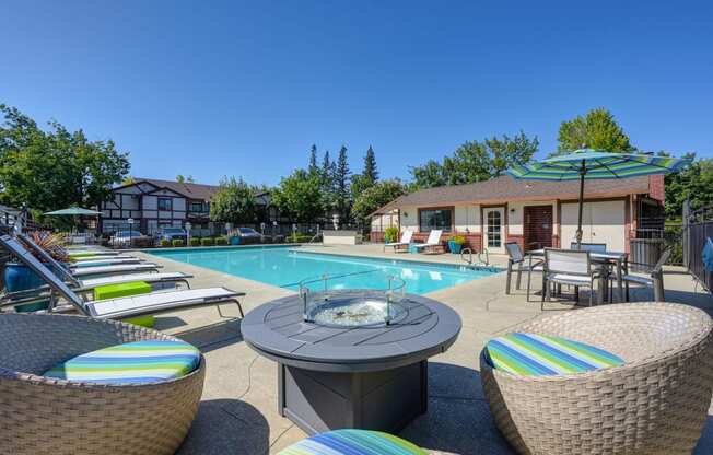 Swimming pool area with chaise lounge chairs, umbrellas, tables and gas firepit