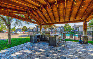 a patio with a table and chairs under a wooden roof