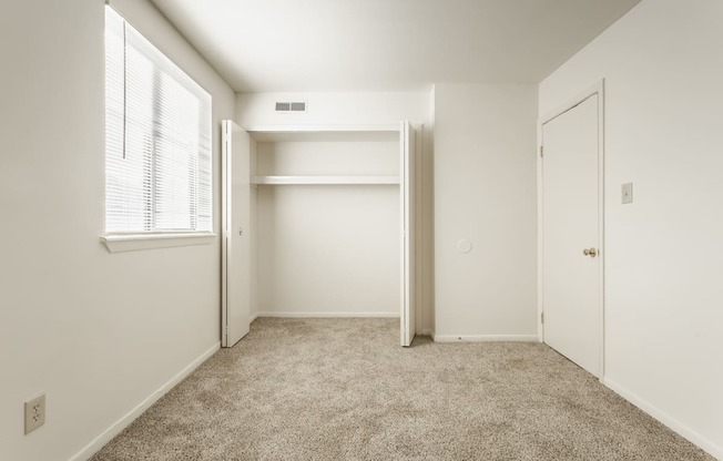 an empty bedroom with a closet and a window