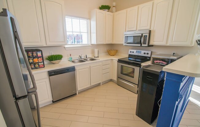 A kitchen with white cabinets and a black fridge.