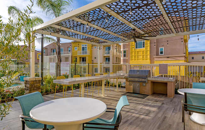 A patio with a table and chairs under a blue and white canopy.