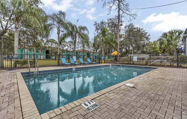 a swimming pool with chairs and a fence around it