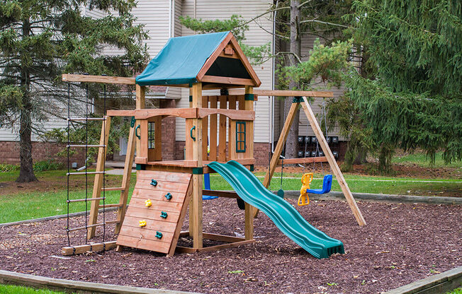 a wooden swing set with a slide in a backyard