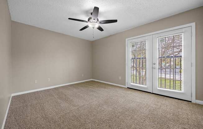 A room with a ceiling fan and carpeted floor.