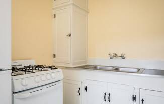a kitchen with white cabinets and a white stove top oven