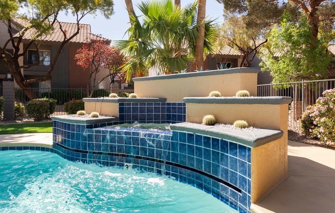 a swimming pool with a blue tiled fountain in a backyard