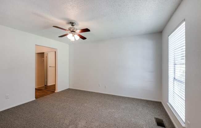 the living room of an empty house with a ceiling fan