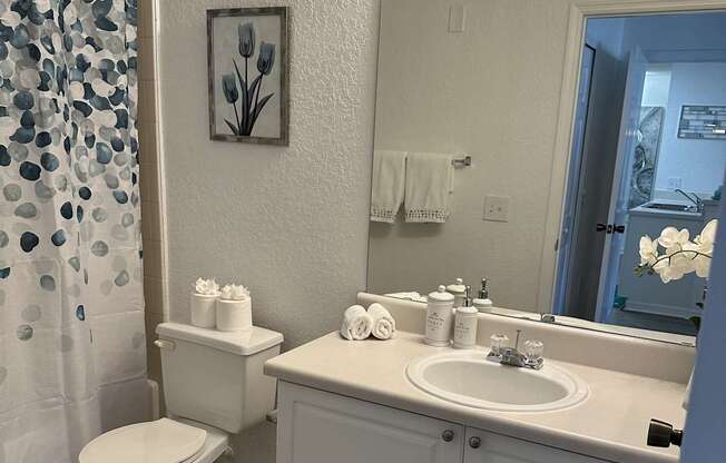 A white bathroom with a toilet, sink, and mirror.