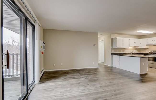 an empty living room and kitchen with a sliding glass door