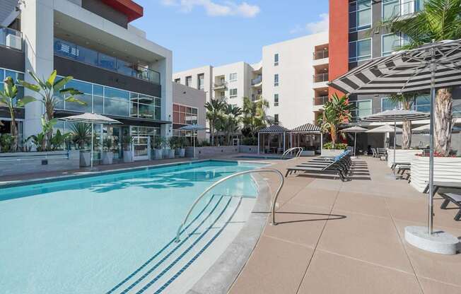 A swimming pool surrounded by lounge chairs and umbrellas.