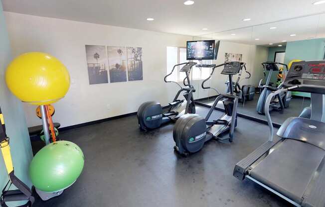 Stationary bikes, treadmill reflected in mirrored wall of fitness center