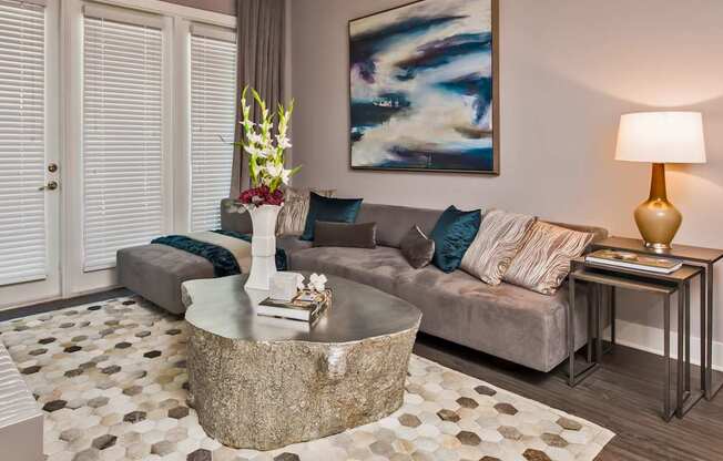 A living room with a grey couch, a coffee table, and a painting on the wall.