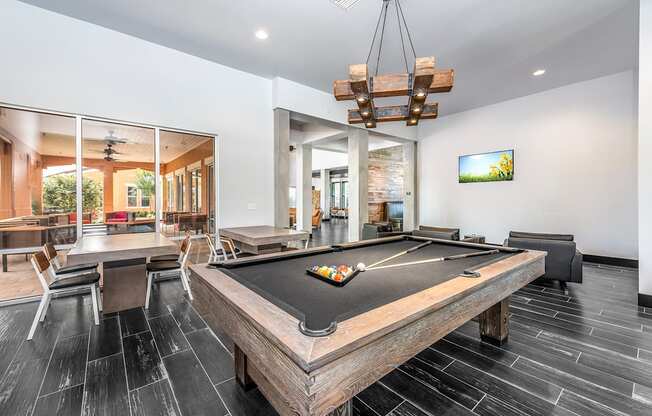 a pool table in the clubhouse of a home with a bar and a dining area