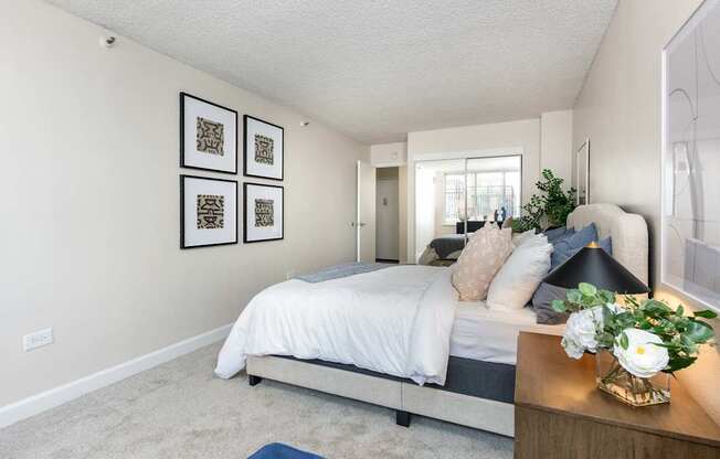 a bedroom with white walls and a bed with white sheets and pillows