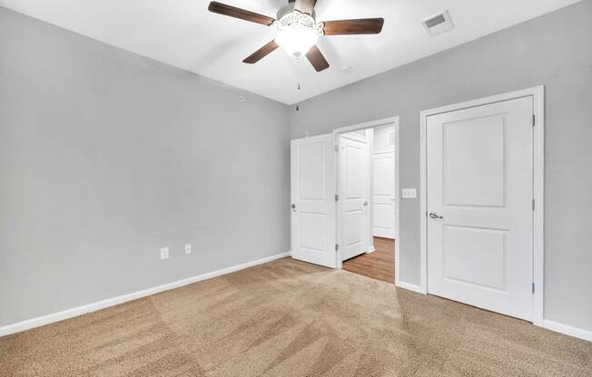 a bedroom with two doors and a ceiling fan