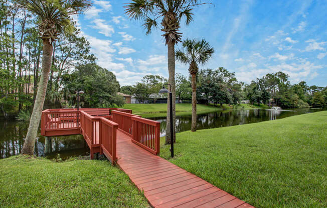 a red bridge over a body of water with palm trees