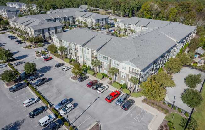 an aerial view of an apartment complex with parking lot and cars