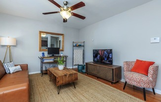 a living room with a ceiling fan and a tv