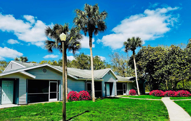 A blue house with palm trees in front of it at Aqua Bay Apartments in Naples, FL 34116