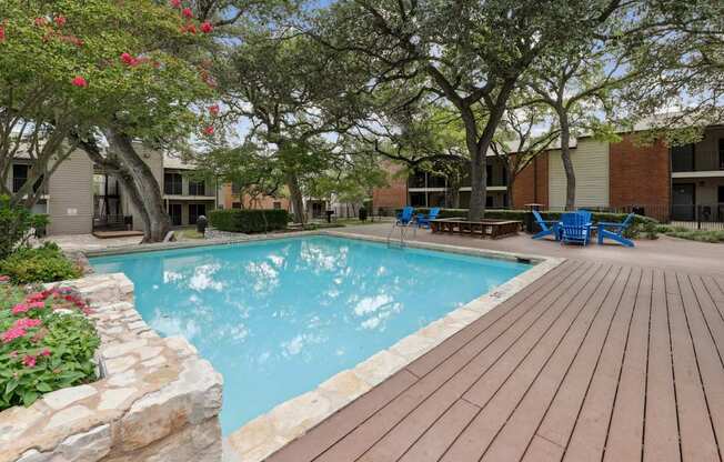 A pool surrounded by a wooden deck and trees at Westdale Pointe in Austin, TX