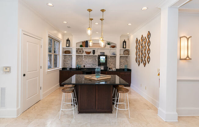 a kitchen with white walls and tiles flooring and a large center island with a black counter