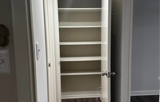 A white door is open to a hallway with a light on the ceiling.