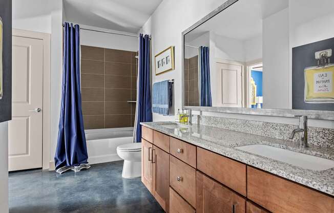 A bathroom with a toilet, sink, and blue curtains.