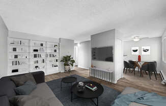 A living room with a grey couch, a black coffee table, and a bookshelf filled with books.