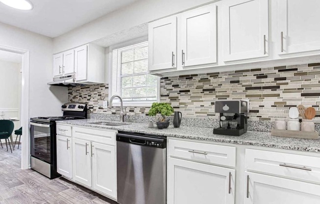 an open kitchen with white cabinets and a counter top at Elea Apartments in Marietta, GA