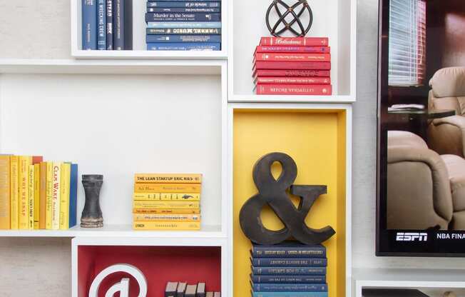 a bookshelf filled with books and a yellow bird on top at The Enclave, Jersey City, NJ