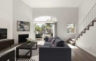 A living room with a grey couch and a black and white striped rug.
