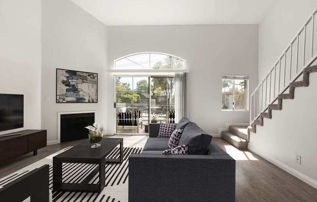 A living room with a grey couch and a black and white striped rug.