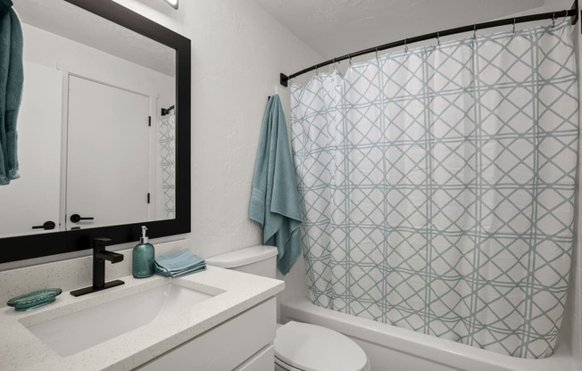 a bathroom with a white sink and toilet next to a bathtub with a shower curtain and