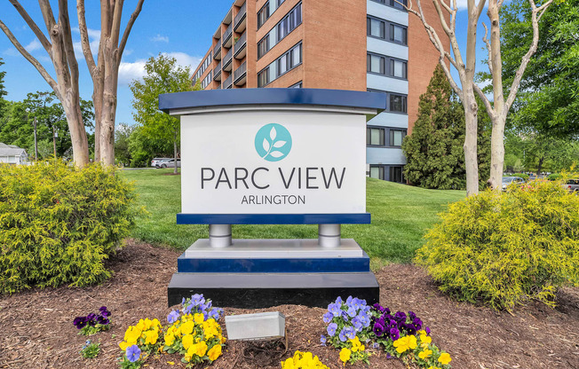 an apartment building with a park view sign in front of flowers