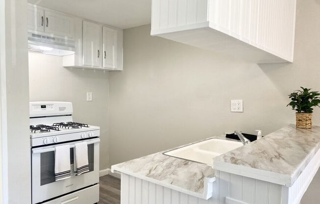 a kitchen with white cabinets and a white stove top oven at South Pointe Apts, Covina, CA