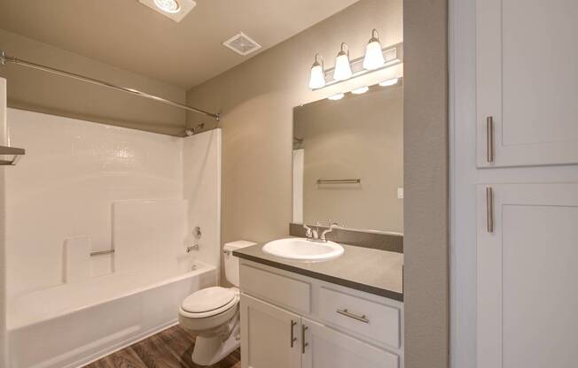 A white bathroom with a toilet, sink, and mirror.