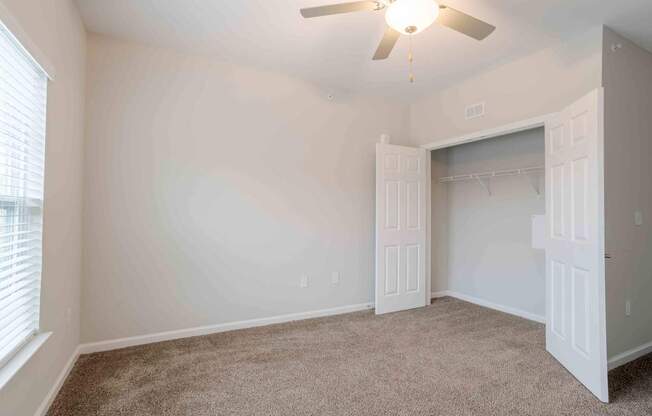 A room with a ceiling fan and a closet.