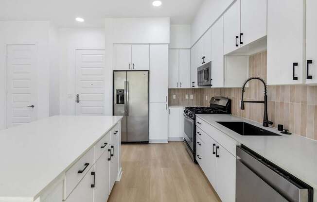A modern kitchen with white cabinets and stainless steel appliances.