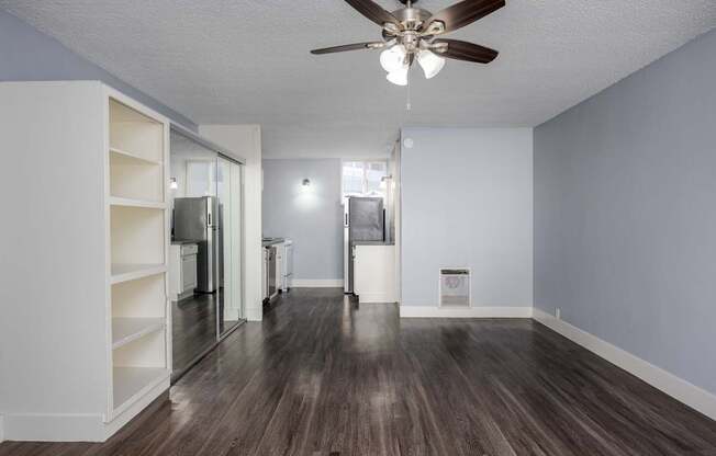 A room with a ceiling fan and wooden flooring.